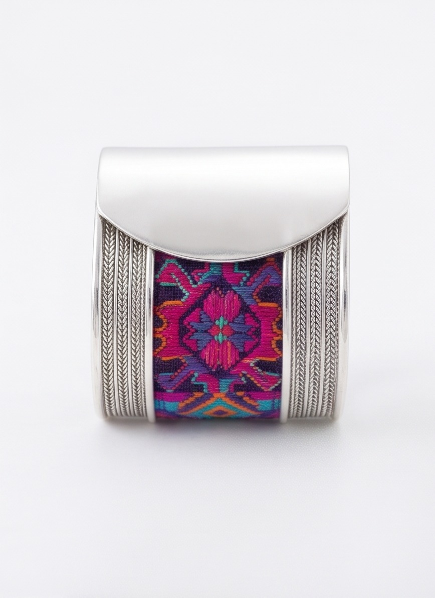 Close view of colorful embroidery framed by engraved silverwork on a bracelet.