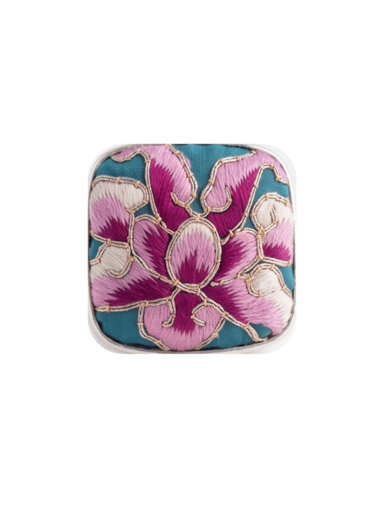 Front view of the square silver-tone ring face with teal, pink, magenta, cream, and gold floral embroidery on a pure white background.