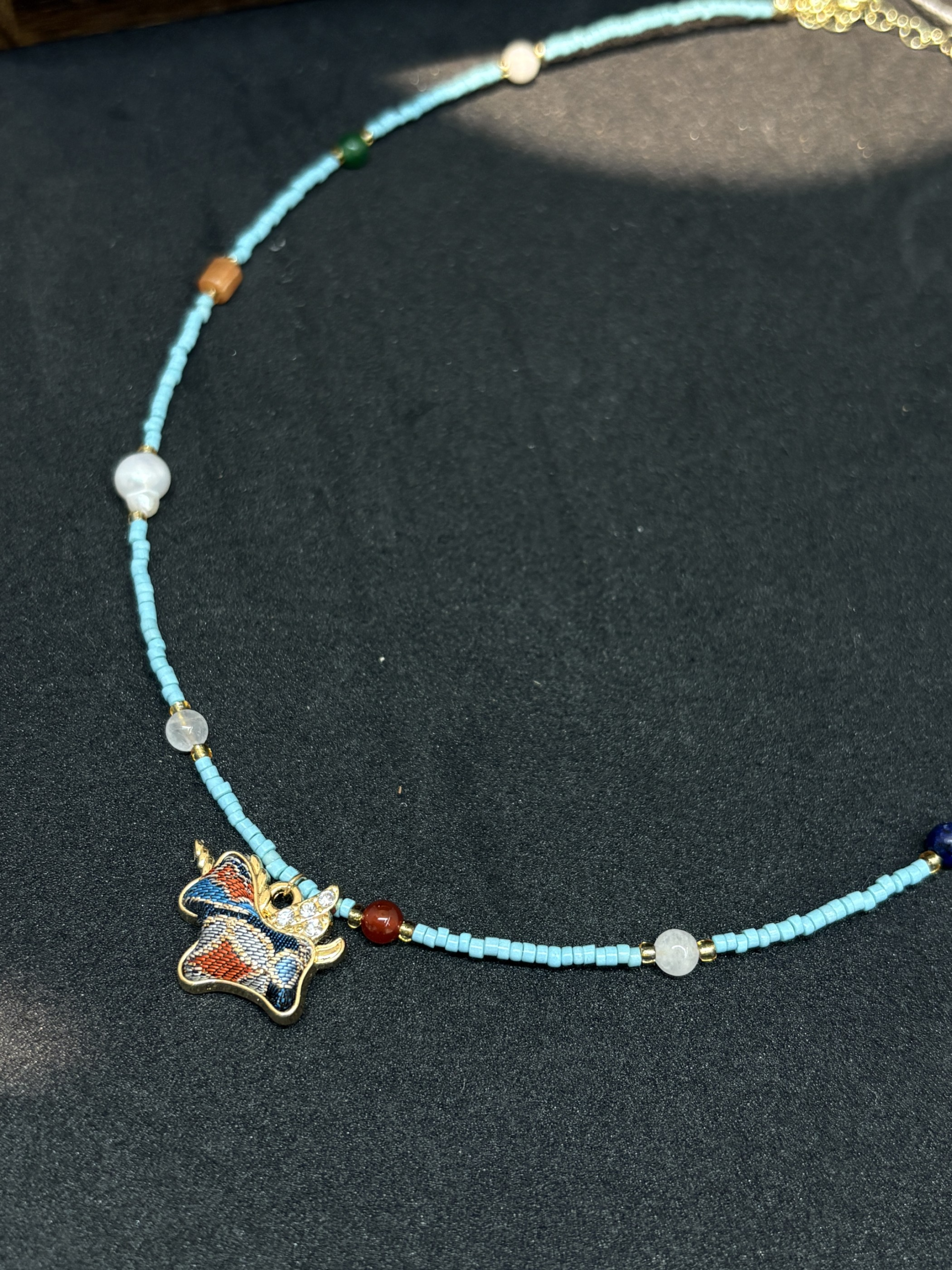 Detail of the necklace’s multicolor Song brocade pendant and nearby beads.