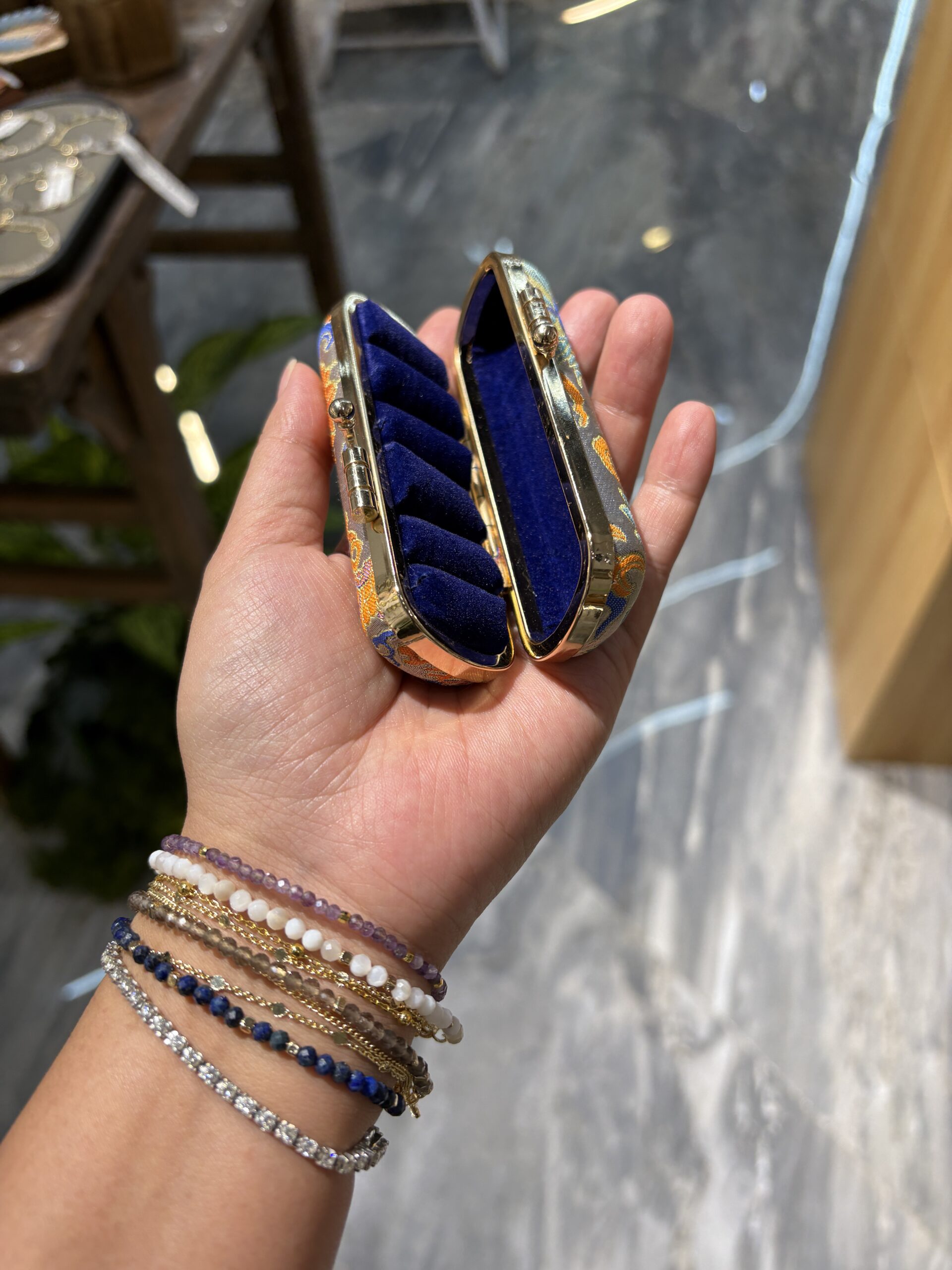 Actual orange kit open in a hand, showing five deep-blue cushioned ring positions and an open compartment.