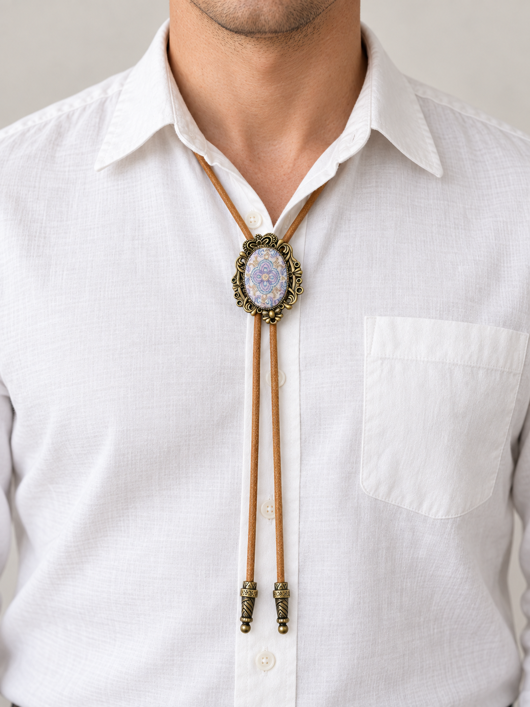 Adult model wearing the pale blue and lavender oval bolo tie with tan cord and two engraved antique-brass-color tips.