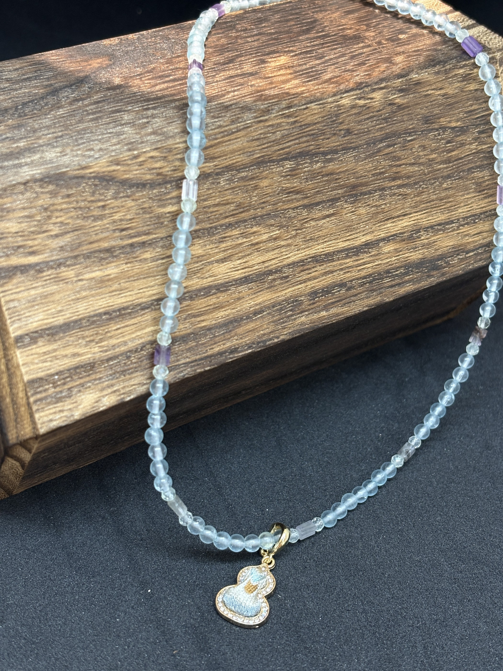 Actual necklace and Song brocade pendant photographed on a dark surface