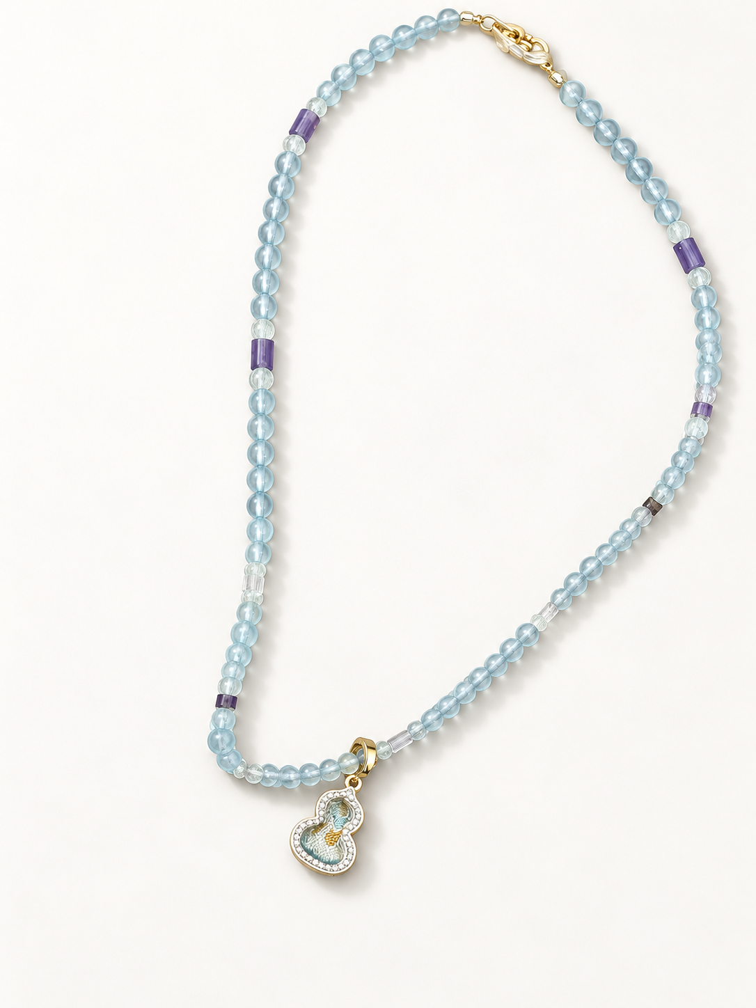 Angled view of the blue and purple beaded necklace and patterned Song brocade pendant