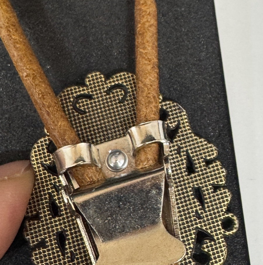 Rear view of the oval bolo tie slide attached to tan cord.