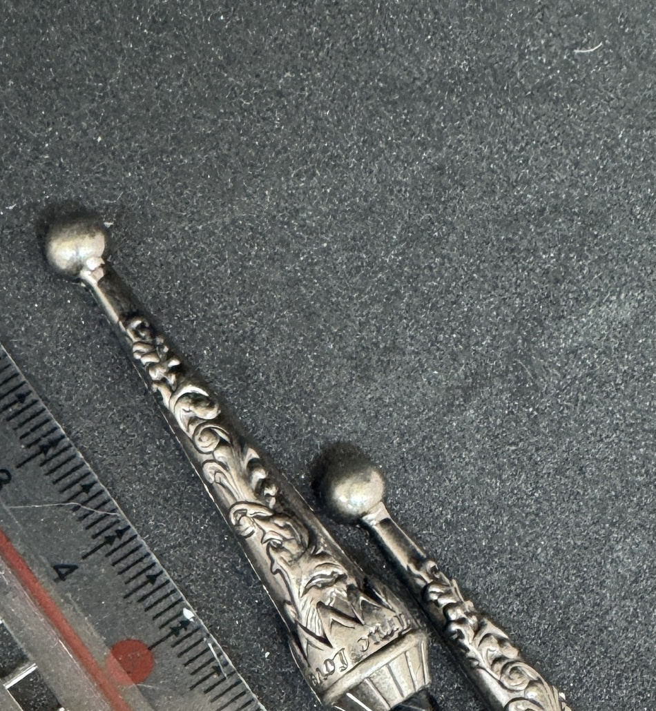Close view of the long engraved silver-color tips on the black braided bolo tie cord.