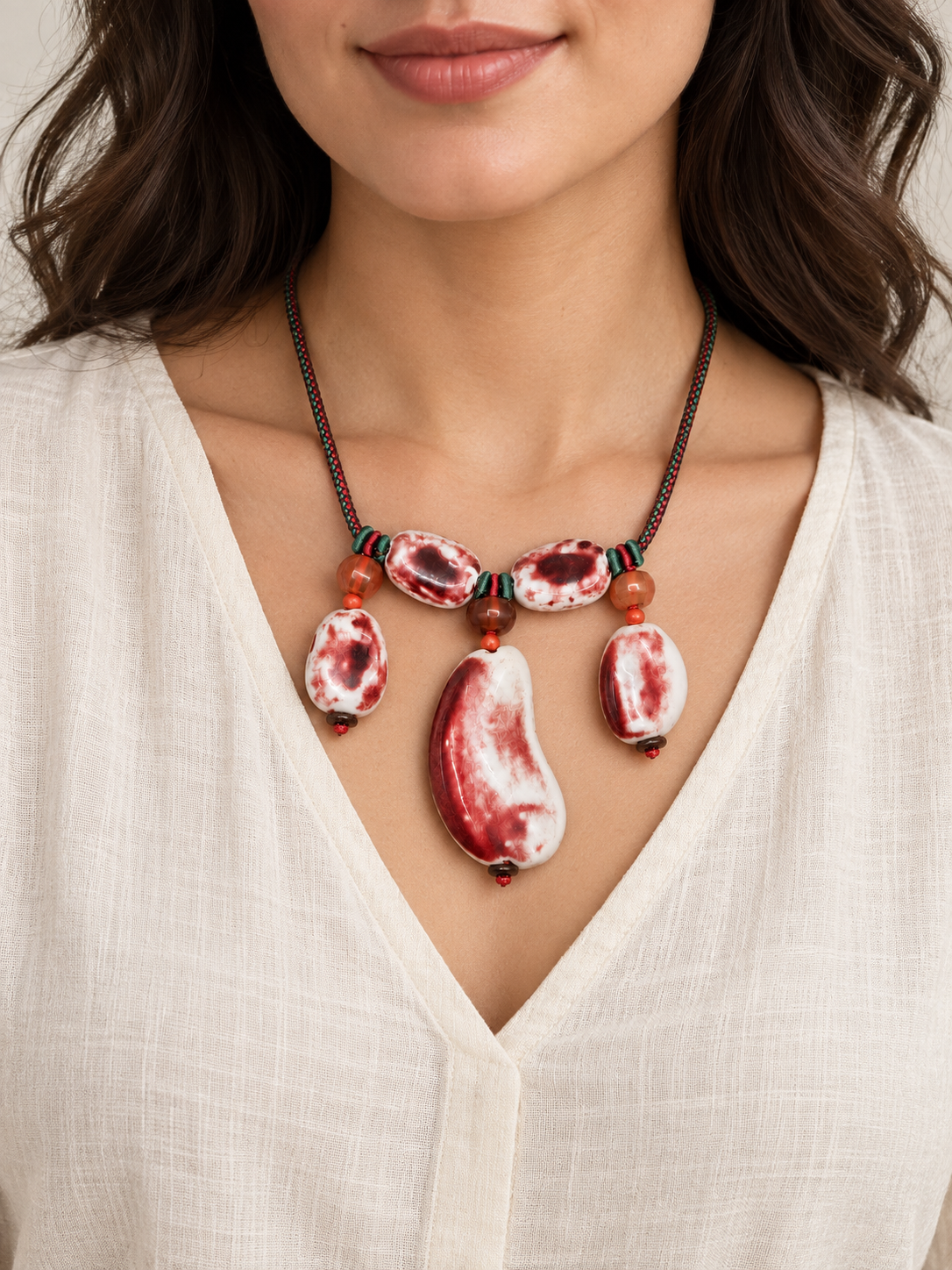 Red and white ceramic statement necklace worn with an ivory blouse.