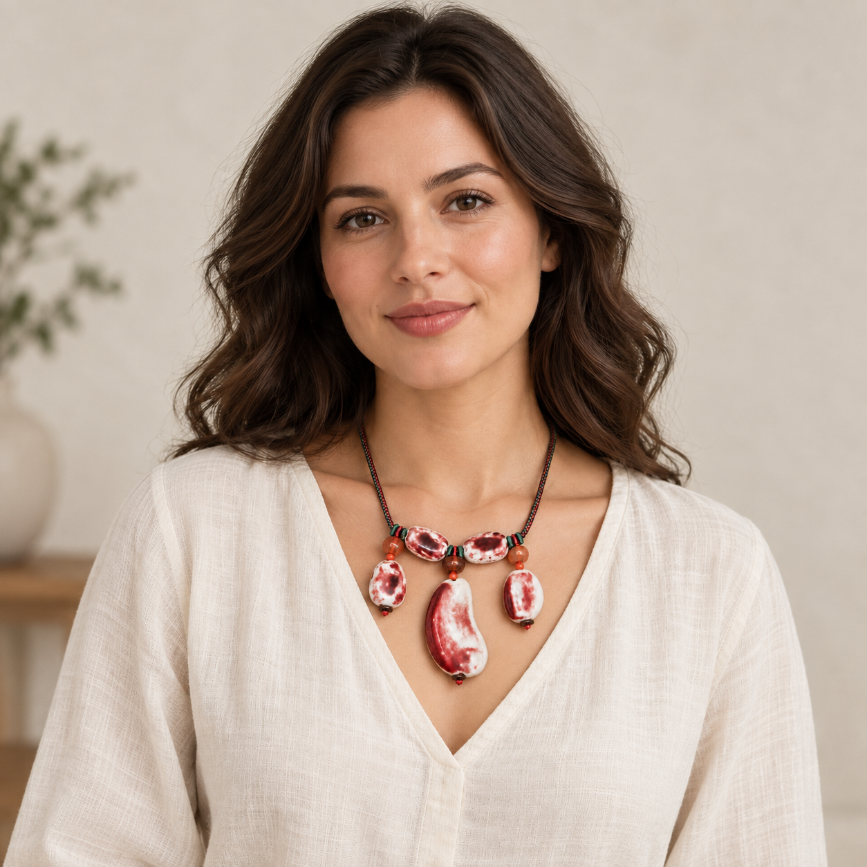 Full-face lifestyle view of a woman wearing the red and white ceramic necklace.