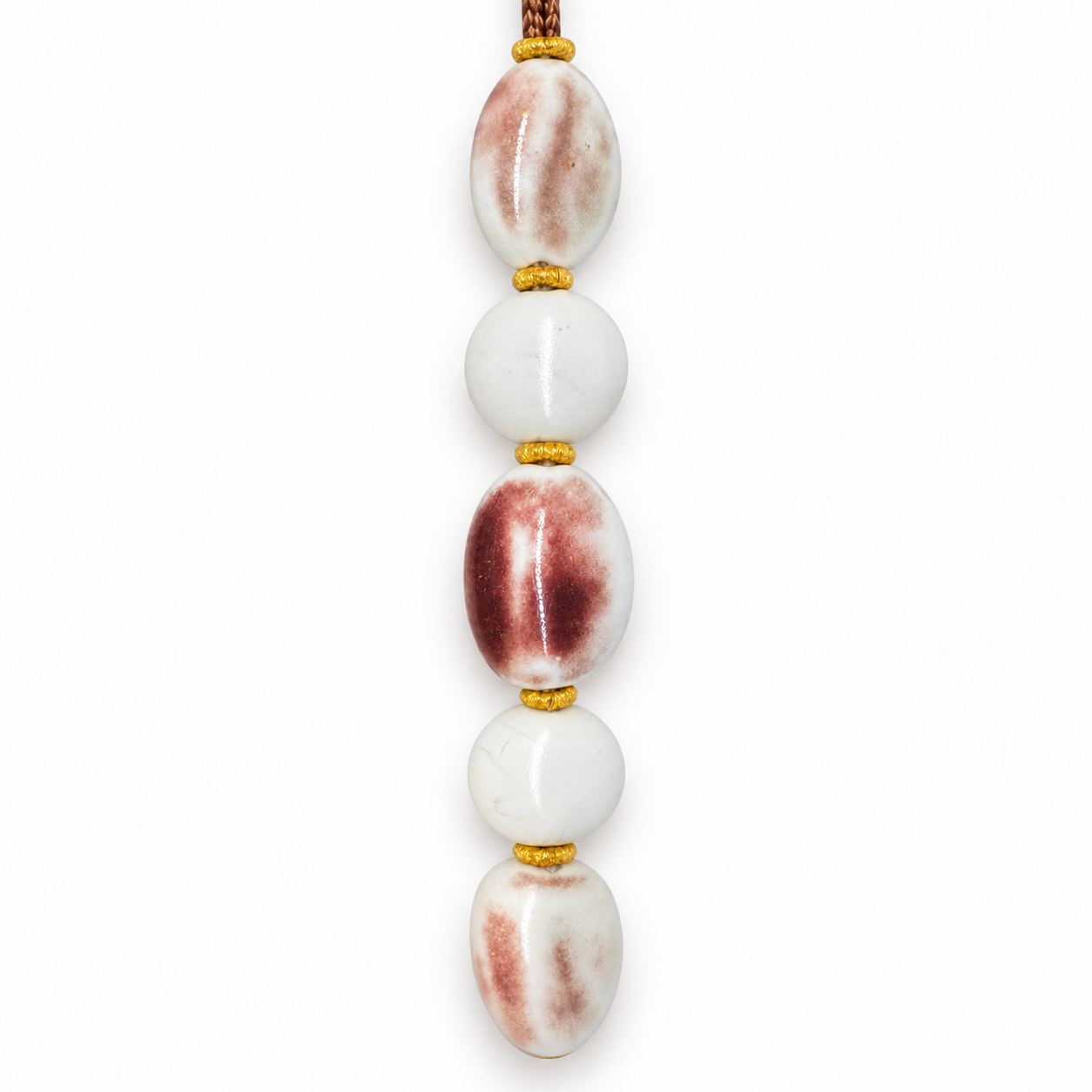 Upright detail of pale and maroon-blushed ceramic beads with gold-color spacers.