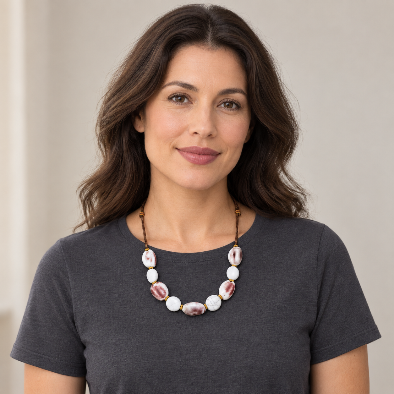 Full-face lifestyle view of a woman wearing the maroon and white ceramic necklace.