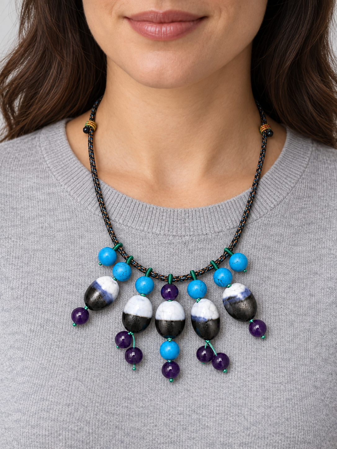 Blue purple black and white ceramic fringe necklace worn with a gray knit top.