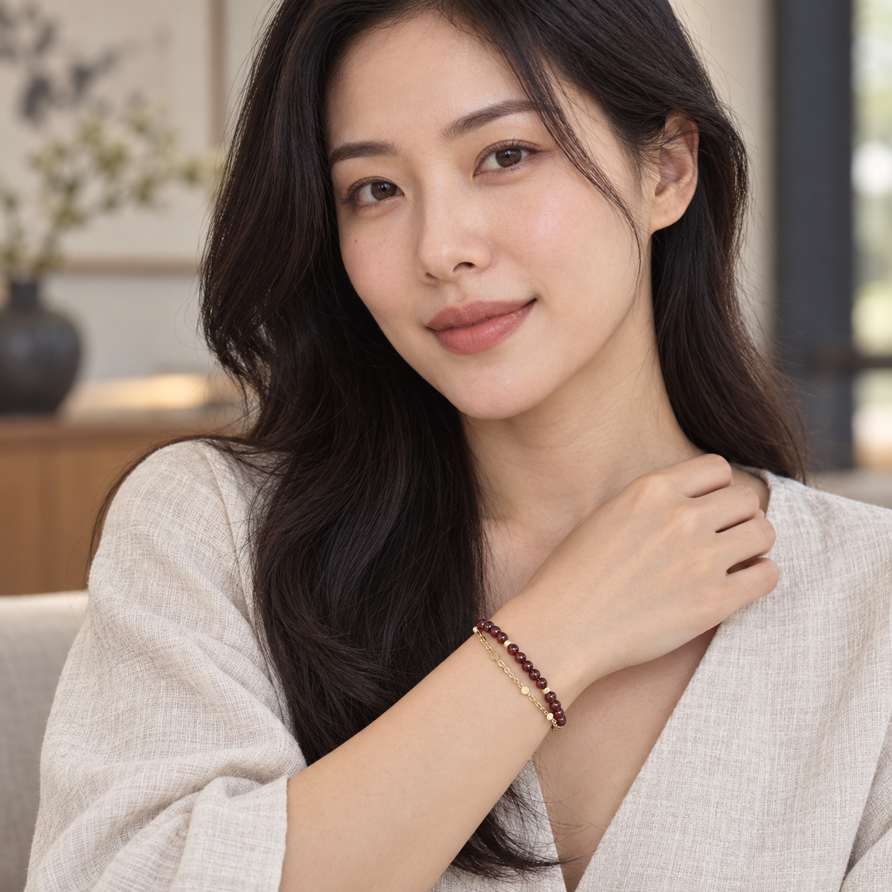 Adult model wearing the burgundy-red and gold-tone double-strand bracelet.