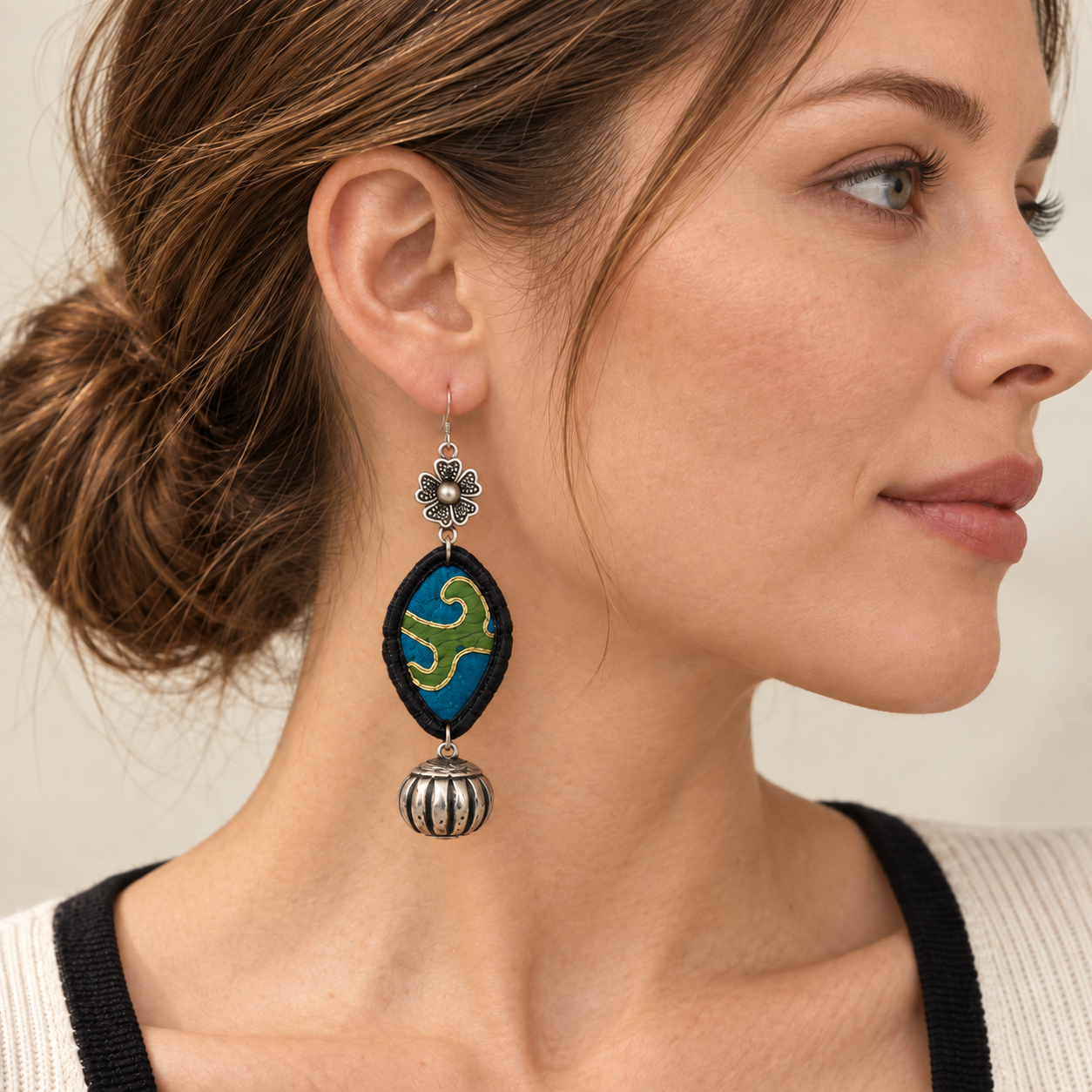 Close portrait showing one Blue-Green Miao Embroidery Bell Earring worn at the ear.