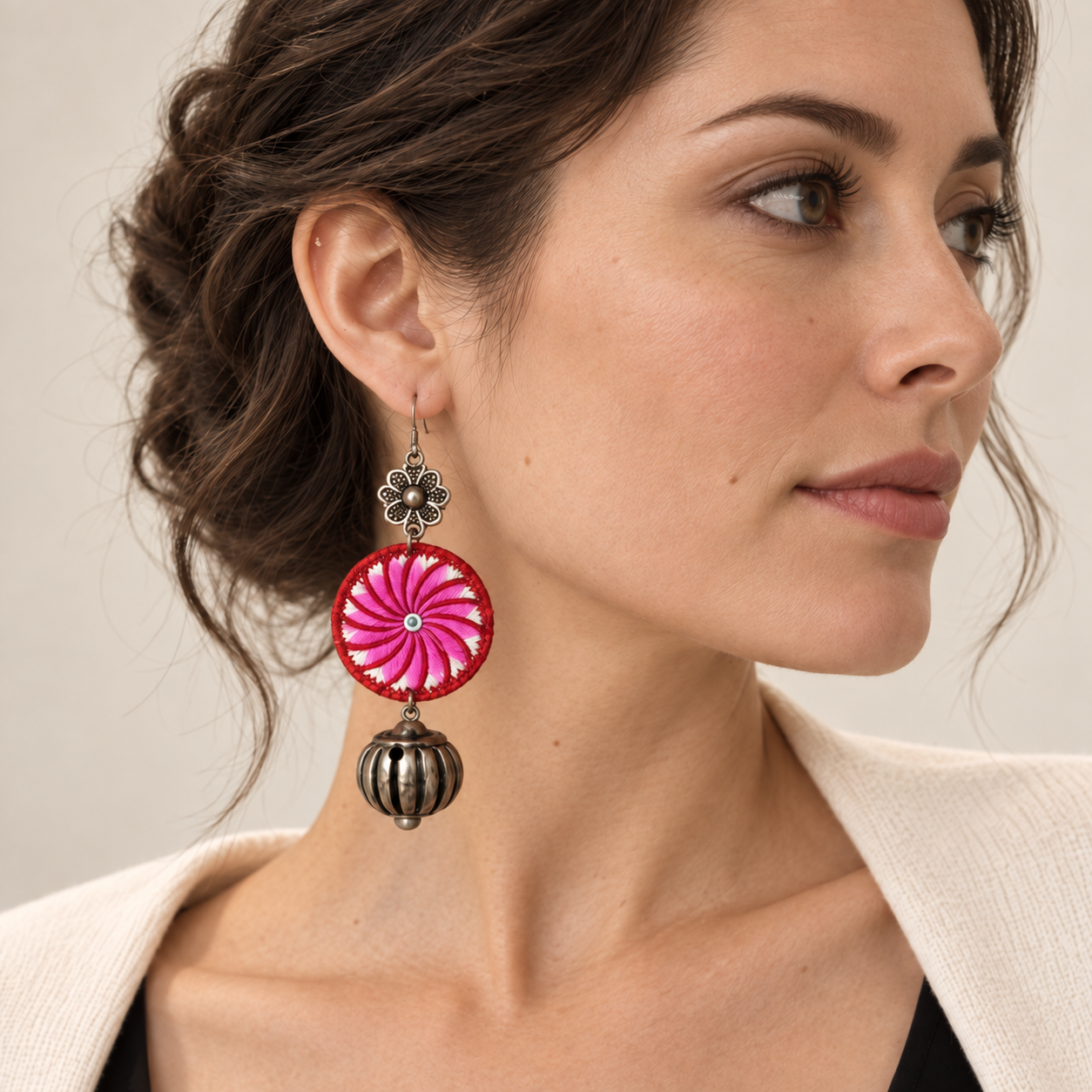 Close portrait showing one Pink Spiral Miao Embroidery Bell Earring worn at the ear.